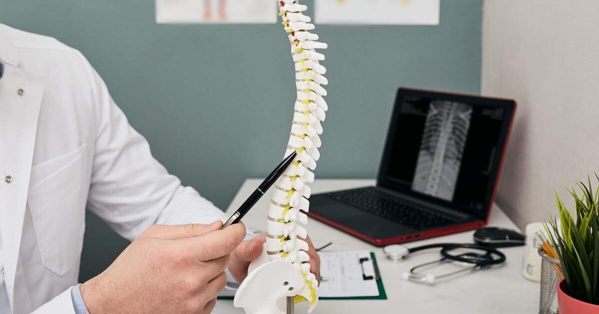 doctor holding a spine module while sitting at a desk  