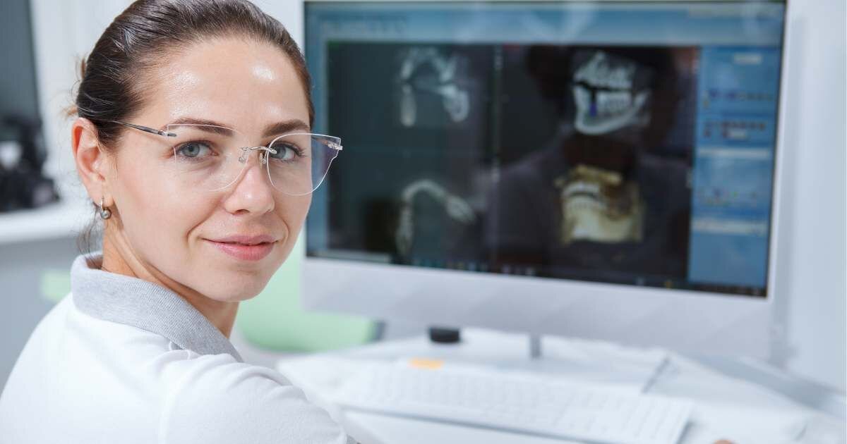 face view of female with x ray scans present on computer screens in the back 