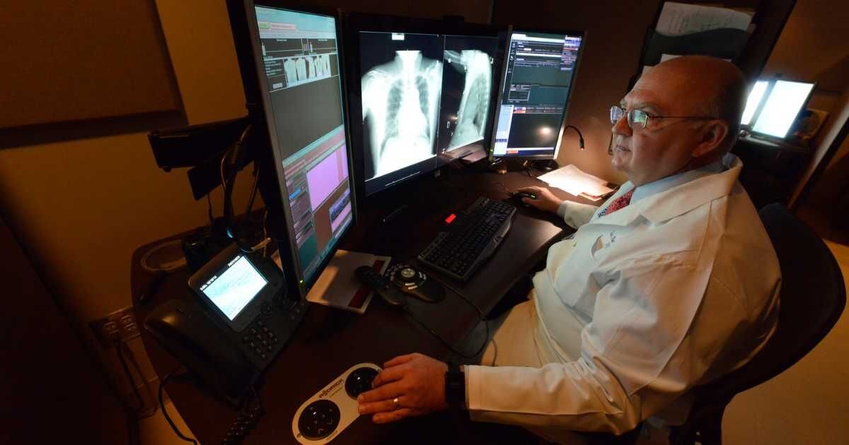 radiologist sitting at workstation viewing patient scans 