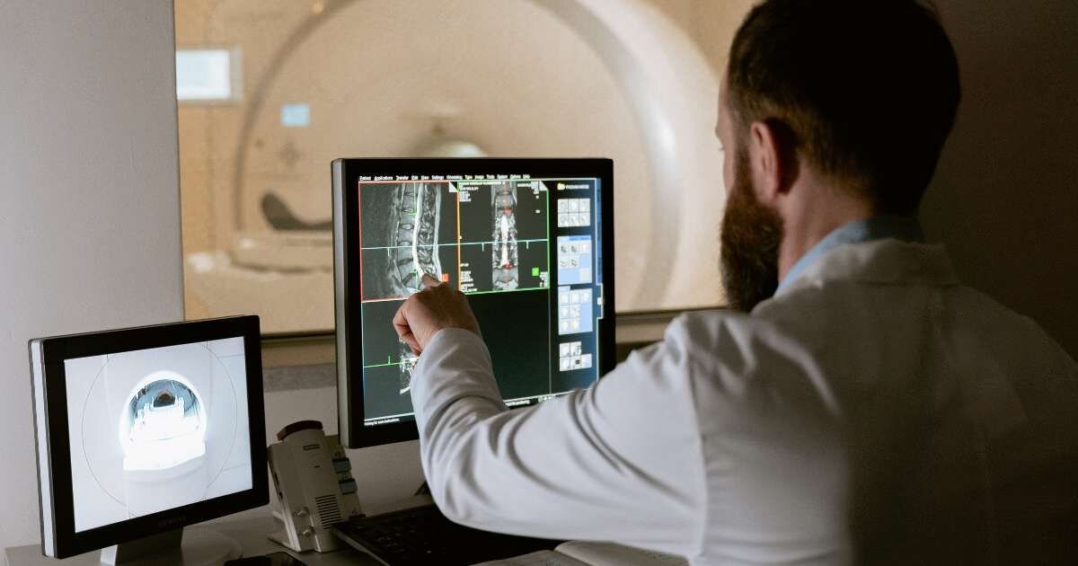 radiologist pointing at patient scans on computer screen 